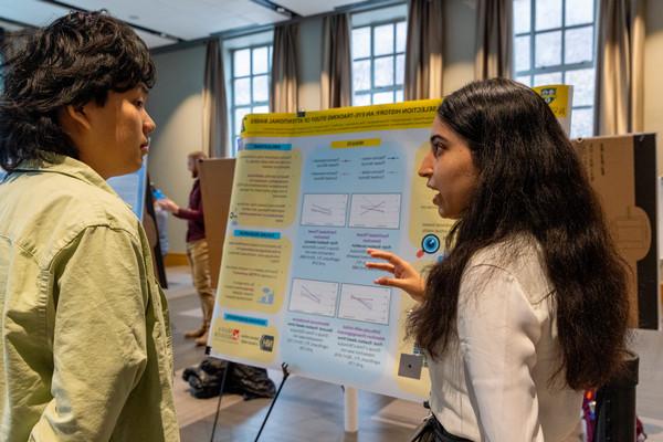 Two students discuss research poster.